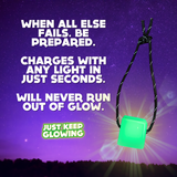 Green glow in the dark emergency light cube, rechargeable, battery-free, hangs by a cord. Just Keep Glowing.