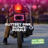 Glittery pink glow in the dark motorcycle license plate frame emitting a purple glow, enhancing visibility and adding a unique, stylish touch to a motorcycle at night. Just Keep Glowing.